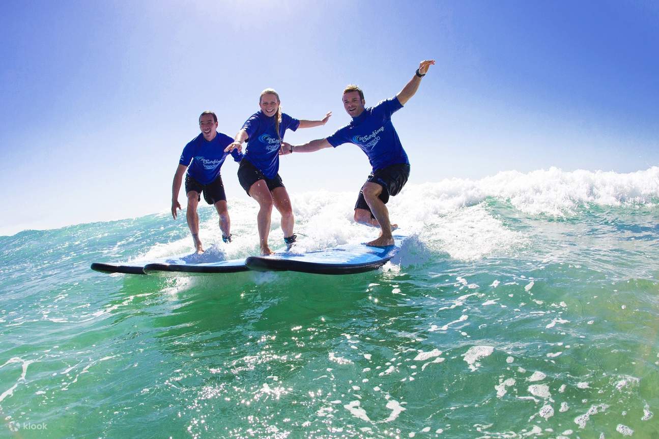 Surfers walking along the beach at sunset carrying boards at an Australian surf camp