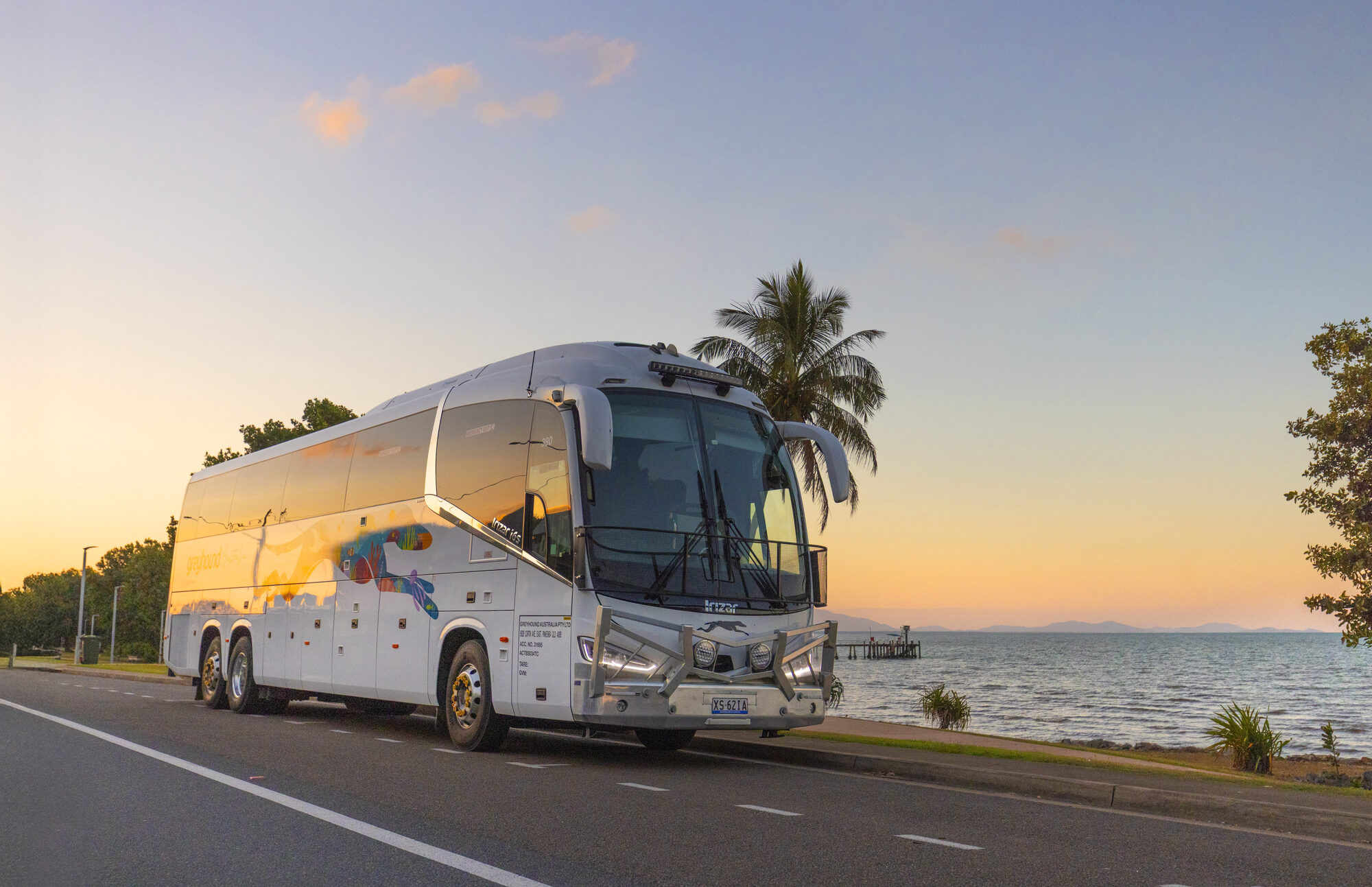Greyhound coach parked in a golden grass field under a big Aussie sky