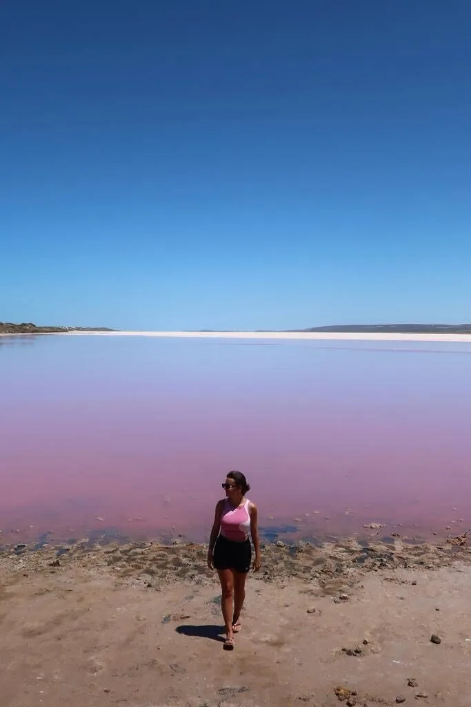 Traveller standing beside the bright pink water of Hutt Lagoon on the Western Australia coast