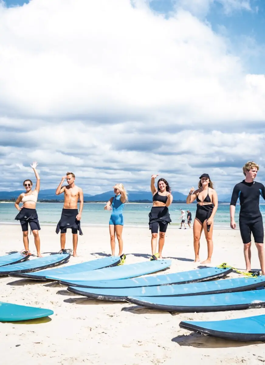 Backpacker surfing at sunrise on Australia’s East Coast during the Brisbane to Sydney Surf Bus tour