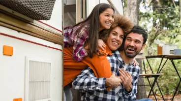 Happy family leaning out of a campervan door at a campsite