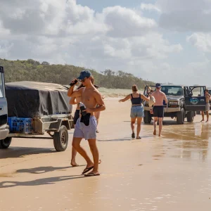 Travellers standing near 4WD vehicles on the beach during Fraser Island tour