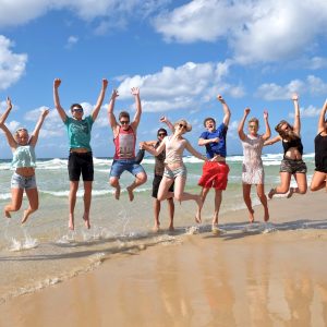 Group of travellers jumping in the air on the beach during Fraser Island tour