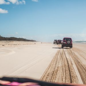 4WD convoy driving along long sandy beach on Fraser Island coastline
