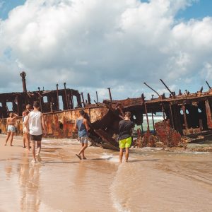 Travellers walking along beach next to Maheno Shipwreck on Fraser Island