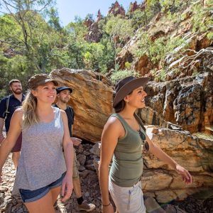 Group hiking through rocky canyon trail in the Australian Outback