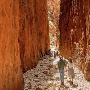 Couple walking through narrow red rock canyon passage in Central Australia