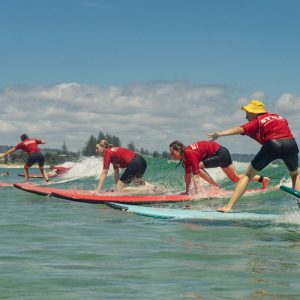 Beginner surfer riding a wave at Rainbow Beach on the Australian Surf Bus