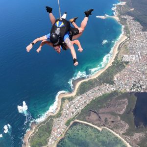 Tandem skydivers in freefall above Wollongong coast and blue ocean
