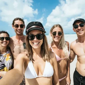 Group of young travellers taking a selfie on Whitehaven Beach during an adventure tour in Australia