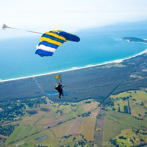 Tandem parachute flying over Byron Bay beach and coastline aerial view