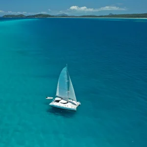 Sailing Catamaran Entice anchored in clear turquoise tropical waters under blue sky