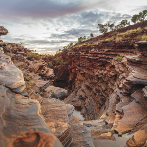 Stunning view of a rocky red canyon in Western Australia, showcasing rugged cliffs and deep gorges under a stormy sky.