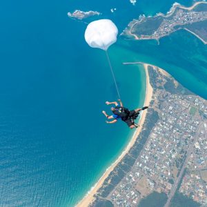 Tandem skydiver descending above Wollongong coastline and ocean
