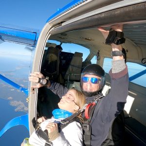 Tandem skydivers exiting aircraft above Wollongong coastline