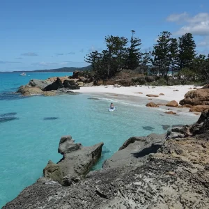 Guest paddleboarding in calm turquoise waters during the Sailing Catamaran O'Nice tour